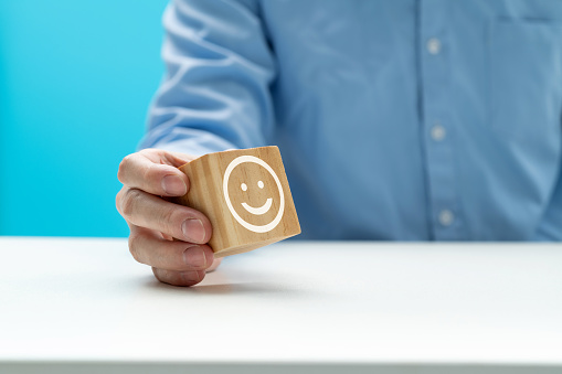 Happy  teen boy holding smile emoji face cover his face, positive mental health concept