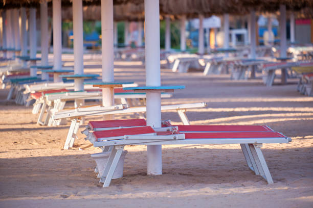 istock Empty deck chairs on sandy beach sea side in summer resort. Vacations and getaway concept 1415219487