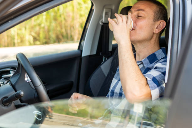 istock Man drinking coffee in a paper cup inside the car 1415222506