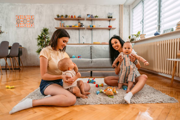 Two young mothers having a play date with their two baby boys in the living room, on the floor.