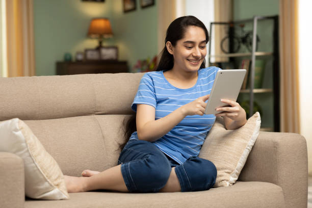 istock girl using digital tablet while sitting on sofa, stock photo 1415227375