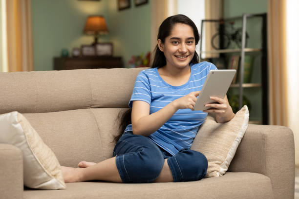 istock girl using digital tablet while sitting on sofa, stock photo 1415227412