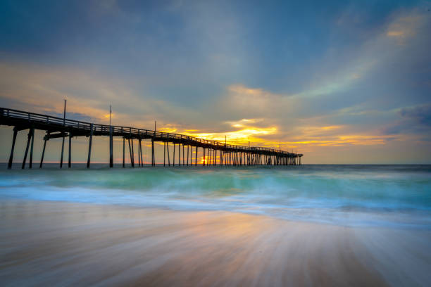 Outer Banks Fishing Pier Feel the peace and tranquility as the sun rises over the Atlantic Ocean behind the fishing pier at Avon, NC on Hatteras Island. outer banks north carolina stock pictures, royalty-free photos & images