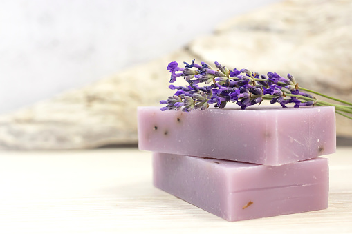 Handmade lavender soap with natural fresh lavender flowers on a gray background. Side view.