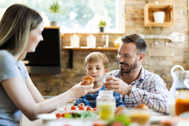 istock Happy parents feeding their  little son in dining room 1415229093