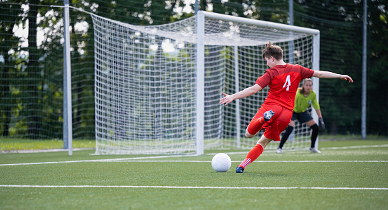 Shot of female soccer player kicking the ball during a match on a stadium. Sport and healthy lifestyle concept.