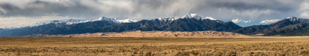 istock Panorama of Great Sand Dunes Below Snow Capped Mountains 1415230082