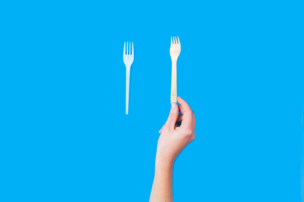 istock Woman hand holding eco natural bamboo fork. Plastic fork vs reusable bomboo comparison concept. Flat lay on blue background. Sustainable lifestyle concept. Zero waste. Choise plastic free itemes. 1415231692