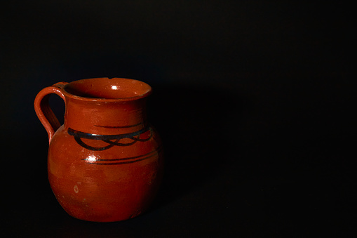 Handmade clay jar with decoration and black background