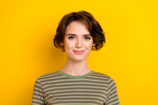 Portrait of young lady looking directly camera cute face isolated on bright yellow color background.