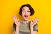 Closeup photo of young attractive girl smiling hands up shocked good prices isolated on yellow color background