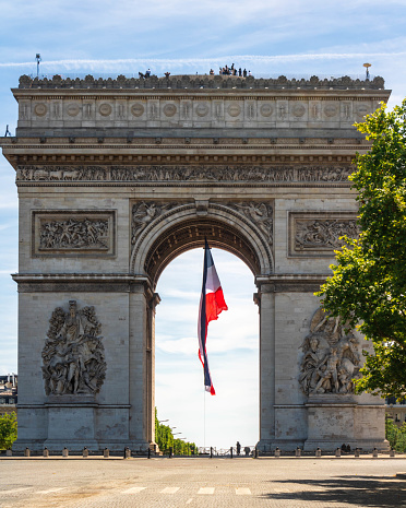 Paris, France - July 14th 2022: A large french flag fluttering under the Arc de Triomphe in Paris, Bastille day