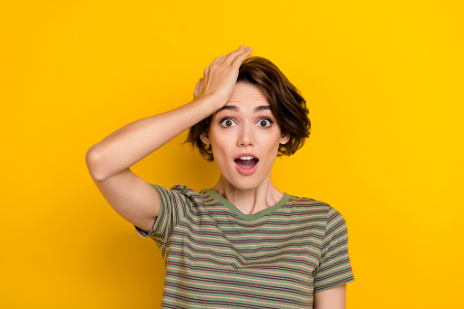 Closeup photo of young funny grimace girl touching head forgot turn off computer home isolated on yelow color background.