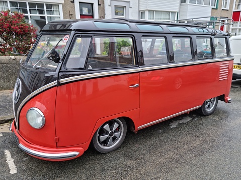 Rhosneigr, Gurnsey, UK. 08/16/2022 Orange and black Volkswagen 1954 T1 transporter bus with split screen parked in a residential street while its owners enjoy the seaside resort.