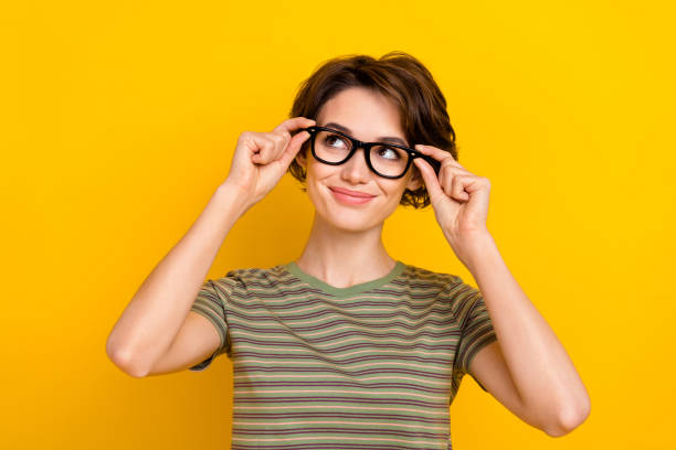Photo of funky dreamy girl dressed green t-shirt arms eyewear looking empty space isolated yellow color background Photo of funky dreamy girl dressed green t-shirt arms eyewear looking empty space isolated yellow color background. eyeglasses stock pictures, royalty-free photos & images