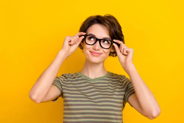 Photo of funky dreamy girl dressed green t-shirt arms eyewear looking empty space isolated yellow color background.