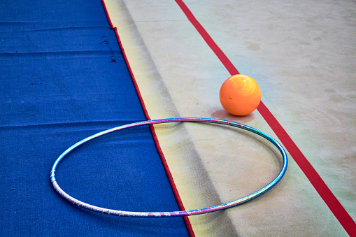 Orange ball, bright hula hoop on a rhythmic gymnastics competition mat