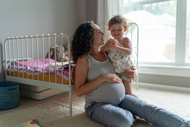 una madre etnica incinta e il suo bambino interagiscono nella scuola materna - human pregnancy toddler child mother foto e immagini stock