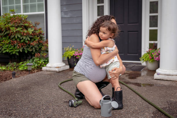 istock A pregnant Mama and her toddler are hugging while taking a break from watering plants together outside 1415235736