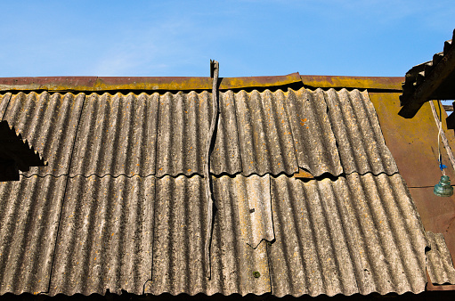 An old wavy slate roof with moss. Texture of old slate with moss. Shed roof covered with old asbestos sheets. Outdoor interior. Texture of old roof, slate background