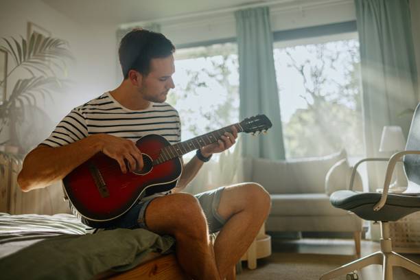 istock Man learning how to play guitar via online classes 1415237150