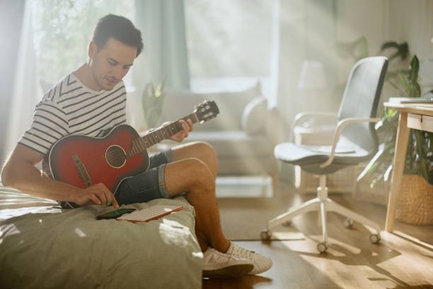 istock Man learning how to play guitar via online classes 1415237181