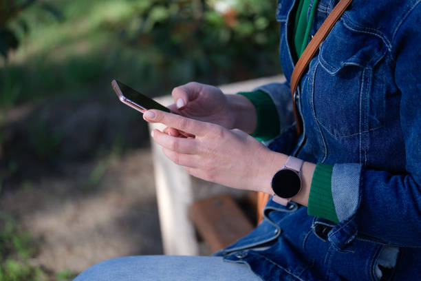 istock Woman sitting on bench is holding smartphone 1415237368
