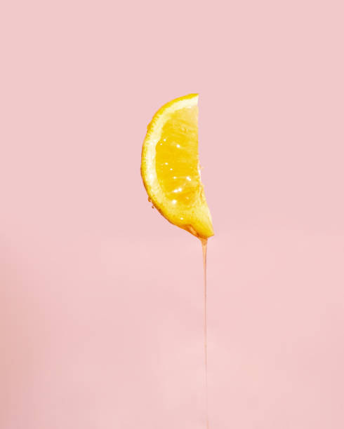 istock Melting honey and lemon on pastel light pink background. Minimalistic fruit concept. Creative summer nature composition. 1415237369