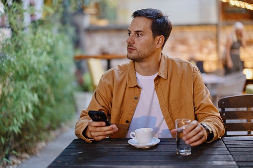Young man sitting and using smartphone at coffee shop