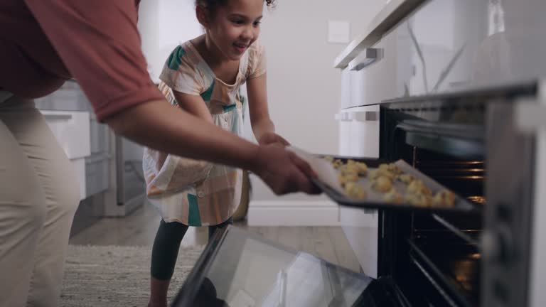 Grandmother and child baking cookies in the family kitchen together as the little girl is learning from helping her elderly granny. Happy senior woman teaching her excited granddaughter to cook