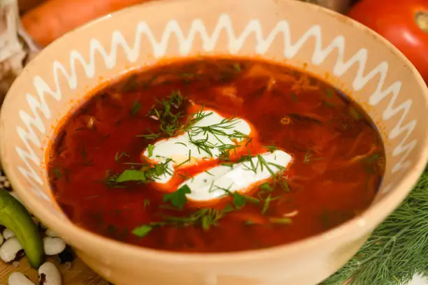Close-up of traditional Ukrainian borscht with sour cream in a clay bowl.