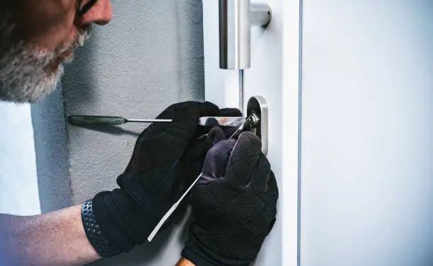 masked burglar with crowbar breaking and entering into a victim's home. motion blur selective focus