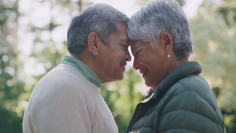 Happy, romantic and senior couple in love, bonding and enjoying the outdoors showing their happiness together. Smiling, loving and mature husband and wife connecting and touching foreheads in nature