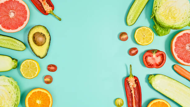 Copy space background with sliced fresh fruits and vegetables on cyan theme. Flat lay HEalthy lifestyle