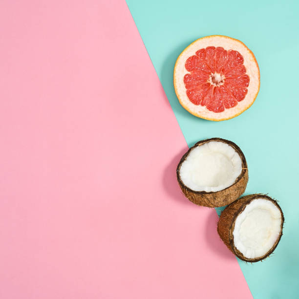 istock Half sliced coconut and grapefruit on pastel pink and cyan background. Flat lay. Creative summer tropical background. Copy space 1415246368