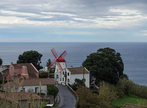 view on village Bretanha with old windmill called Red Peak Mill, Moinho do pico vermelho sea and clouds background, Sao Miguel, Azores.