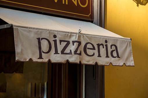 A Pizzeria Awning with the word pizzeria on a facade of a restaurant.