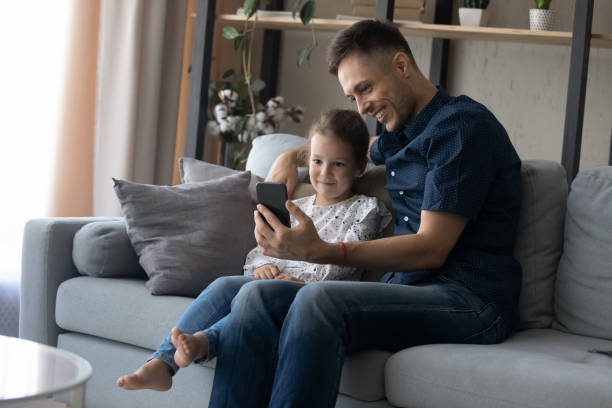 istock Joyful bonding young father and small daughter using smartphone. 1415255190