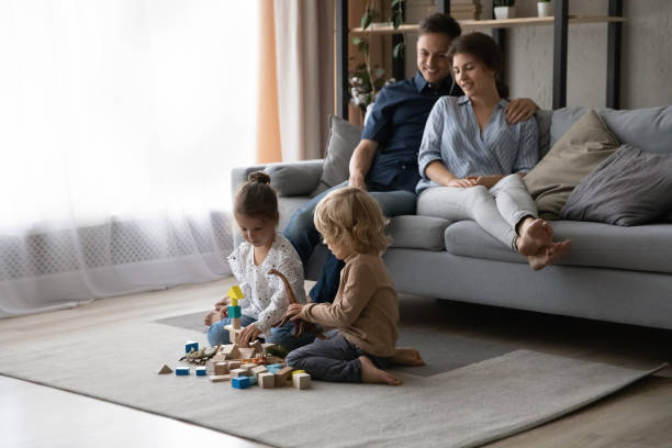 istock Relaxed young c parents watching small children playing at home. 1415255200