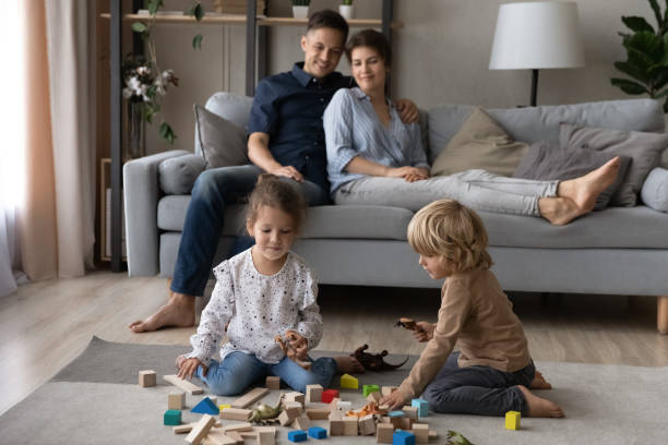 istock Loving parents sitting on sofa while small kids playing toys. 1415255908