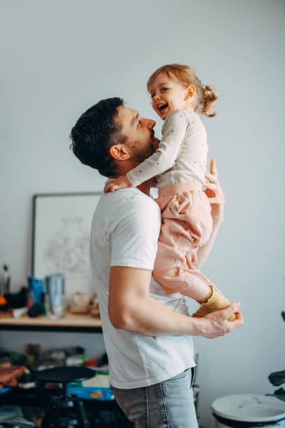 spielzeit mit papa: süßes mädchen, das versucht, das gleichgewicht zu halten, während ihr vater sie hält - fathers family fathers day child stock-fotos und bilder