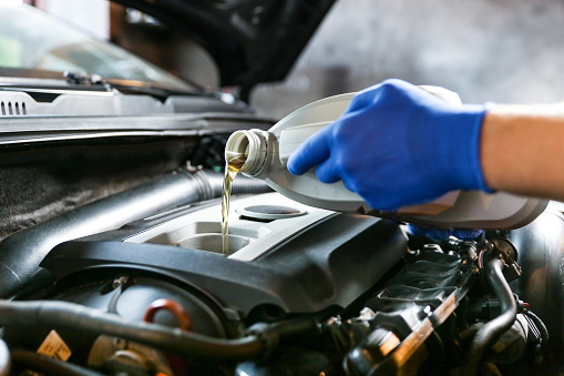 automobile oil is poured into the engine close up. pouring new oil into the engine. car engine oil change