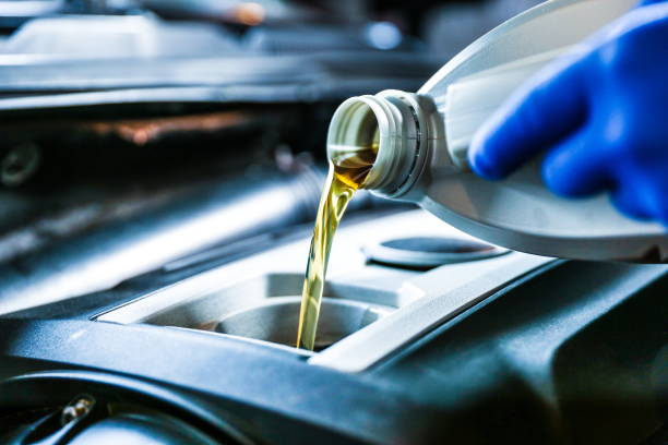 istock car engine oil is poured into the engine close up. 1415260443
