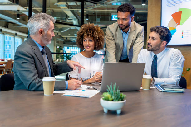 istock Four business people working on a laptop computer in an office. 1415261581