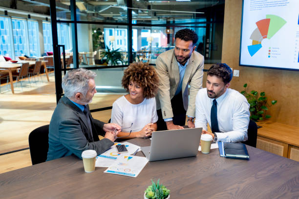 istock Four business people working on a laptop computer in an office. 1415261584