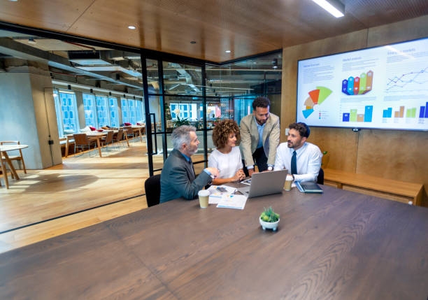 istock Four business people working on a laptop computer in an office. 1415261585