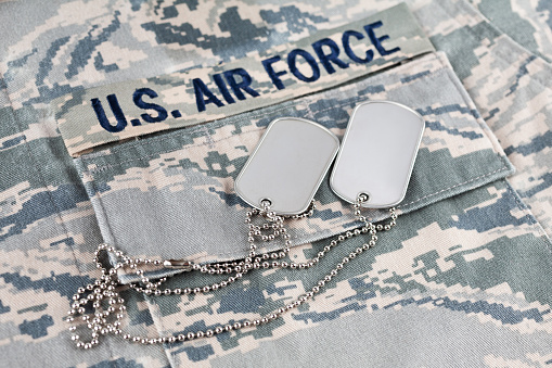 US AIR FORCE branch tape and veteran old type dog tags on digital tiger-stripe pattern Airman Battle Uniform background