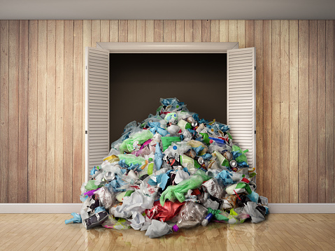 A pile of garbage spills out of the wardrobe. Concept of wasteful.