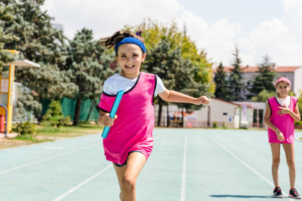 istock kids Passing the relay baton on the track field 1415265310