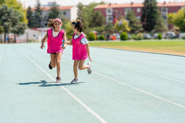istock kids Passing the relay baton on the track field 1415265455